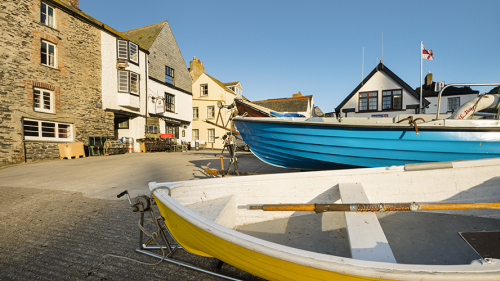 Photo of a yellow and blue boat moored outside of houses